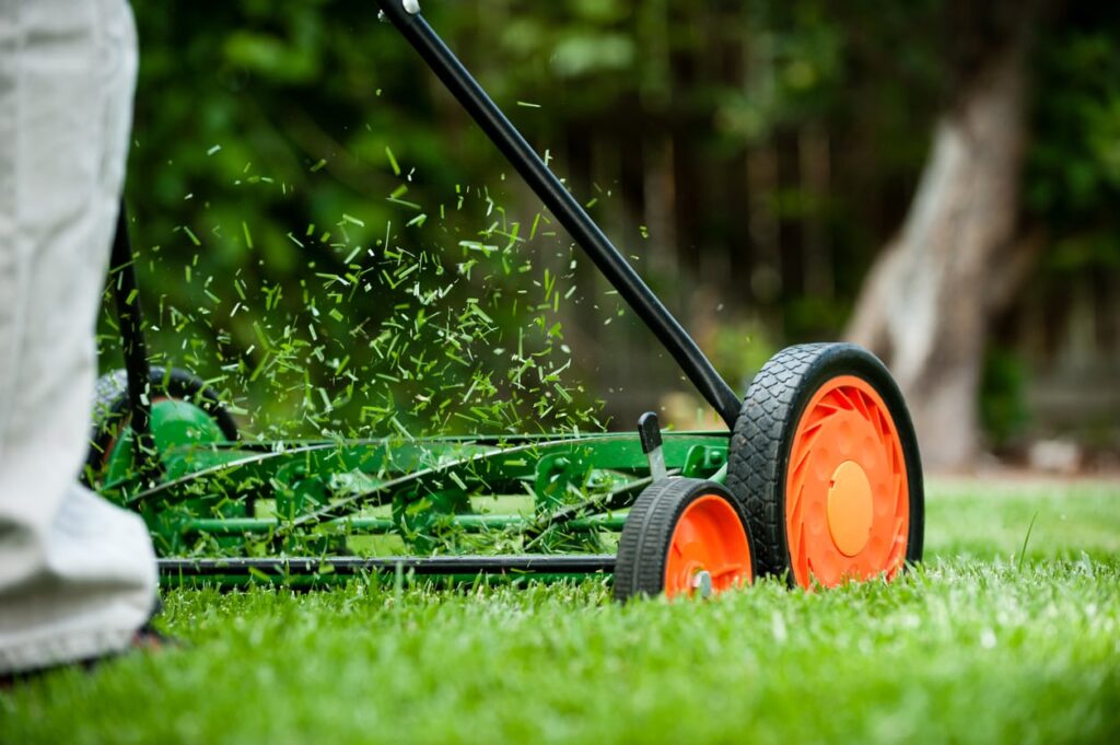 Professional lawn care worker using commercial mower equipment on a well-kept property