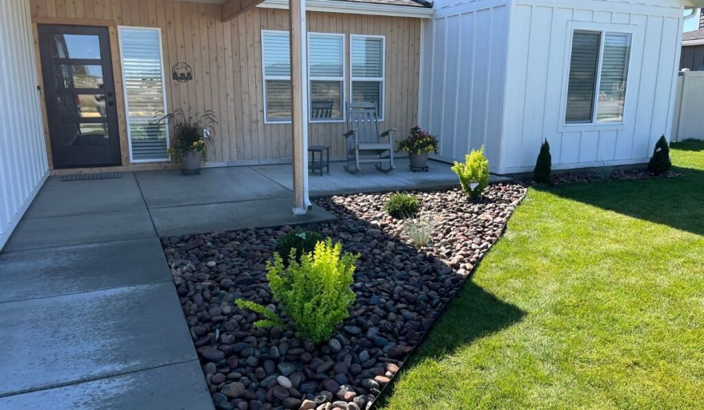 Lawn care professional trimming and cleaning up a residential yard in Flathead County