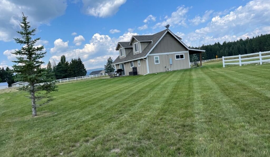 Professional lawn care worker using commercial mower equipment on a well-kept property